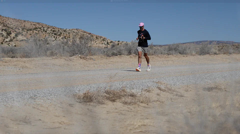 Lachlan running along a road through an open, dry landscape.