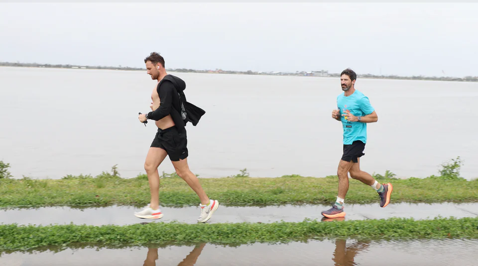 Lachlan running alongside another runner beside the water.